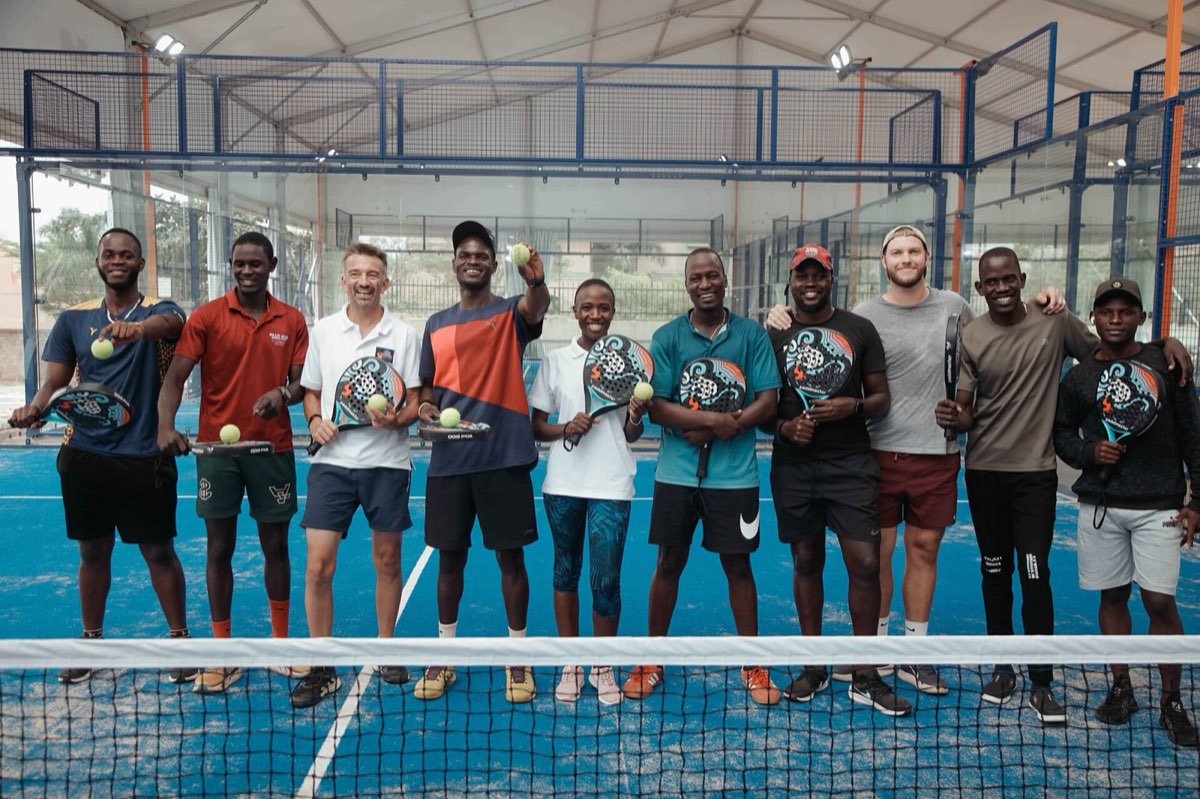 Bir padel kortunda raketleriyle duran karışık bir oyuncu grubu